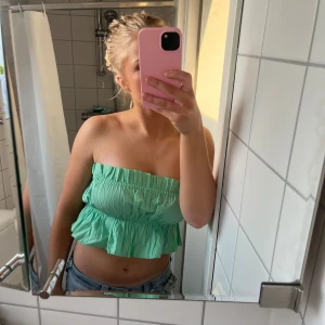 Sommar topp - Säljer en söt mintgrön axelbandslös topp med volangdetaljer. Perfekt för varma sommardagar och ger en fräsch look. Toppen är croppad och har en elastisk passform för extra komfort. Toppen är från stradivarius i storlek S aldrig använd endast testad med prislapp kvar❤️ skriv för fler bilder eller frågor 