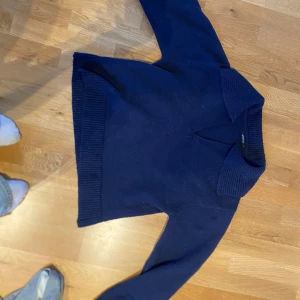 Mörkblå tröja från Gina Tricot - Säljer en stilren mörkblå tröja från Gina Tricot. Tröjan har en v-ringad krage och ribbade muddar vid ärmslut och nederkant. Perfekt för en avslappnad look. Passar bra till jeans eller kjol.