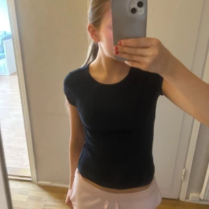 Svart ribbad topp - Svart ribbad topp/ T-shirt. Använd fåtal gånger! Strechigt och skönt material. Färgen är en blandning av mörkgrön och mörkblå 