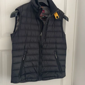 Svart dunväst från Parajumpers - Snygg svart dunväst från Parajumpers med dragkedja och hög krage. västen är köpt i december och har används ett fåtal gånger sen dess. På bilden är jag 178 lång.