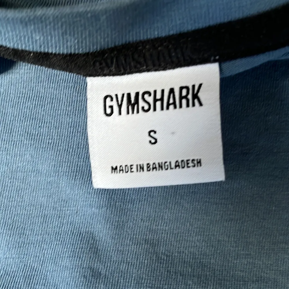 Säljer en stilren blå långärmad tröja från Gymshark. Perfekt för träning eller en avslappnad dag. Tröjan har en diskret logga på bröstet och är tillverkad i ett mjukt material. Är i Smal men Sitter som en medium. Neuletakit & Villapaidat.