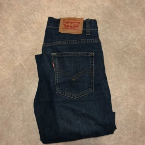 Levi's 511 mörkblå jeans - Mörkblå jeans från Levi's modell 511 med klassisk femficksdesign och raka ben. Jeansen har en brun läderpatch bak i midjan och tydliga kontrastsömmar. Perfekta för en stilren och avslappnad look.