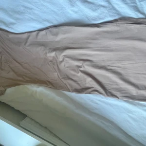 Beige långklänning med kort ärm - Säljer en stilren beige långklänning med korta ärmar och rundad halsringning. Klänningen har en figurnära passform och är tillverkad i ett mjukt, stretchigt material som känns bekvämt mot huden. Perfekt för sommarens alla tillfällen!