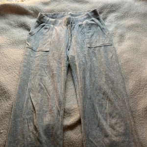 Grå mjukisbyxor från Juicy Couture - Gråa mjukisbyxor från Juicy Couture med dragsko i midjan, fickor fram och bak samt broderad logga på ena benet. 