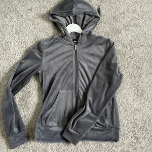 Grå velour hoodie från Gina Tricot - Mjuk och skön grå hoodie i velour från Gina Tricot. Tröjan har dragkedja framtill, huva med snören och två fickor. Perfekt för en avslappnad och trendig look.