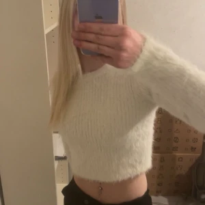 Vit fluffig croppad tröja - Säljer en supermjuk och fluffig vit croppad tröja med lång ärm. Perfekt för dig som vill ha en mysig och trendig look. Passar snyggt till både jeans och kjol.