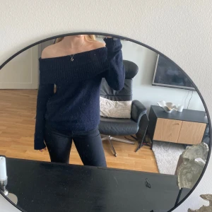 Mörkblå offshoulder stickad tröja - Säljer en mörkblå stickad tröja med offshoulder-design. Tröjan har lång ärm och en avslappnad passform, perfekt att styla med jeans eller kjol. Superfin till vardags när du vill känna dig lite extra.