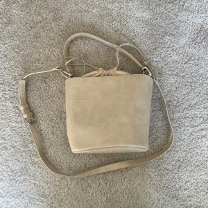 Beige väska  - Super fin väska i perfekt storlek🤍Axelbandet går att ta av, endast använd en gång 💕Mått: 19 cm x 24 cm (Säljer för högst 50 kr då jag vill bli av med allt)