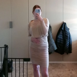 Beige långärmad klänning från SHEIN - Säljer en beige långärmad klänning från SHEIN med rund hals och resår i midjan. Klänningen har en tight passform över höften och är tillverkad i ett mjukt, stretchigt material. Perfekt för dig som gillar enkel och stilren design.