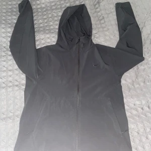 Svart vindjacka med huva från Nike - Säljer en Helt ny oanvänd windbreaker eftersom den inte passade, har kvitto