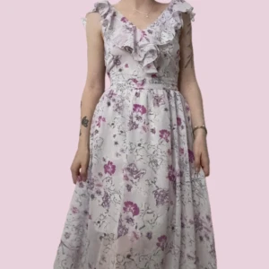 Blommig långklänning med volang från Gina Tricot -  Långklänning från Gina Tricot med blommigt mönster i lila och rosa toner. Klänningen har volang vid ringningen, är ärmlös och har en djup v-ringad rygg. Aldrig använd! Super fint skick! :)