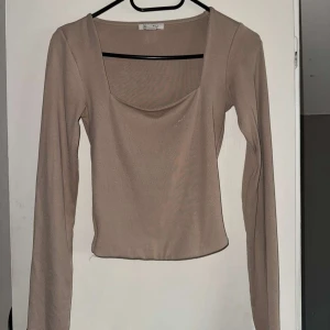 Beige långärmad topp från Amisu - Säljer en beige långärmad topp från Amisu i storlek XS. Toppen har en snygg, något croppad passform och en bred, rundad ur ringning💕