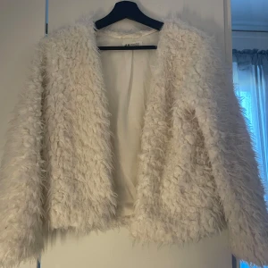 Vit pälsjacka från H&M - Säljer en fluffig och trendig vit pälsjacka från H&M.