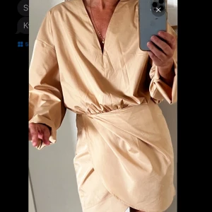 Beige omlottklänning från Stylein - Klänning Jayne dress från Styelin i beige. Strl S. Använd 1 gång. Nyskick. Dragkedja i sidan. Underkjol. 