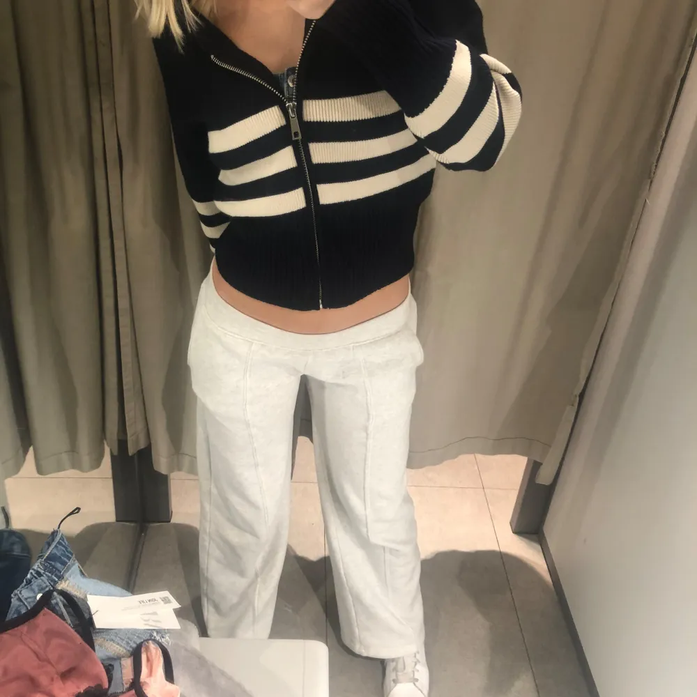 Snygg marinblå kofta med vita ränder och dragkedja framtill. Perfekt för en stilren look. Koftan är croppad och har långa ärmar.. Neuletakit & Villapaidat.