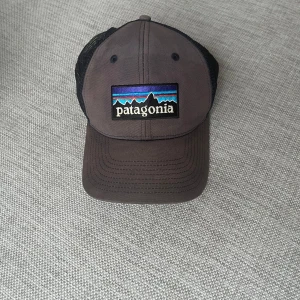 Svart keps från Patagonia - Snygg svart keps från Patagonia med broderad logga framtill. Kepsen har ett justerbart spänne baktill och meshmaterial för bra ventilation. Perfekt för utomhusaktiviteter och vardagsbruk. Den är solblekt men förutom det i fint skick utan skador.