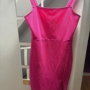 Rosa klänning  - Snygg rosa klänning med en smickrande passform och slits framtill. Perfekt för en kväll ute eller en speciell tillställning. Axelbandslös design som ger en elegant look.