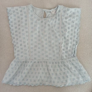 Ljusblå volang topp från Zara - Söt ljusblå topp från Zara med broderade detaljer och volang nedtill. Storlek 140 men passar mig som brukar bära XS. Toppen har korta ärmar och en knapp i nacken. Perfekt för en somrig look! 💙 