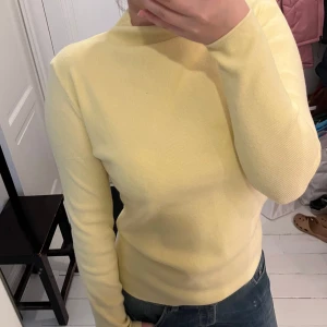 Gul stickad polotröja - Säljer en stilren gul polotröja med långa ärmar. Perfekt för att hålla sig varm och snygg under kyligare dagar. Tröjan har en enkel design som gör den lätt att matcha med olika outfits.