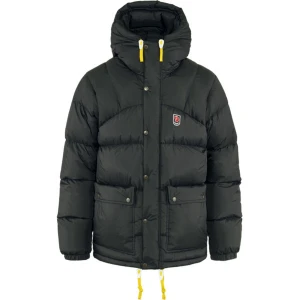 Svart dunjacka från Fjällräven - Snygg svart dunjacka från Fjällräven med huva och gula detaljer. Jackan har knappar och dragkedja framtill samt praktiska fickor. Perfekt för kalla dagar. Ett litet litet hål i höger ärm, enkelt att laga