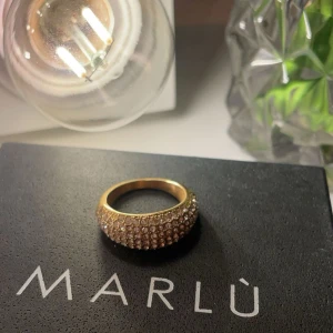 Guldfärgad ring från Marlù - Elegant guldfärgad ring från Marlù, dekorerad med glittrande stenar som täcker hela ytan. Perfekt för att ge en lyxig touch till din stil. Ringen är vattentålig och färgar inte av sig!