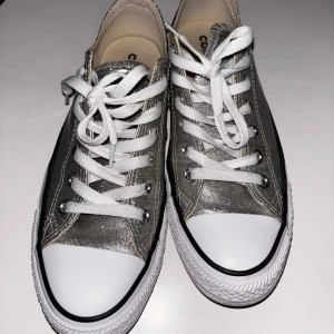 Glittriga Converse sneakers - Snygga glittriga Converse sneakers i silver med klassisk vit gummisula och snörning. Perfekta för att ge din outfit lite extra bling. De är supercoola och svåra att få tag på. Använda 1 gång och väldigt fint skick.🩶🩶