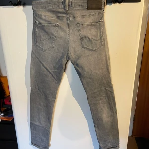 Grå jeans från Jack & Jones - Snygga grå jeans från Jack & Jones i modellen Slim/Glenn. De har en slim passform och är tillverkade i ett bekvämt material. Perfekta för en stilren look. Pris kan diskuteras