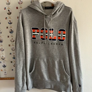 Grå hoodie från Ralph Lauren - Säljer en stilren grå hoodie från Ralph Lauren med stor POLO-logga i svart, rött och vitt på bröstet. Tröjan är ovanlig så de är bara att slå till!💸Perfekt för en avslappnad stil och nu till våren💐🌹Var inte rädd för att ställa fler frågor🐶