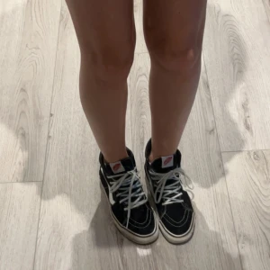 Svarta sneakers från Vans - Säljer ett par klassiska svarta Vans sneakers med vit sula och snörning. Skorna har den ikoniska sidostripen i vitt och är perfekta för en avslappnad stil. De är märkta som världens #1 skateboard shoe. Storlek 37 men tror även passar för 38, säljer de då de är för små för mig.