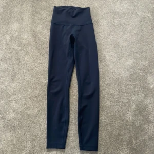 Mörkblå  leggings från Lululemon - Säljer ett par mörkblå  leggings från Lululemon. De är högmidjade och har en tight passform, perfekta för träning eller en aktiv vardag. Materialet är mjukt och stretchigt för bästa komfort.