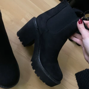 Svarta boots med klack - Snygga svarta boots i mocka med en rejäl block klack och grov sula. Perfekta för att ge lite extra höjd och stil. De har en enkel design utan snörning eller dragkedja. De kommer från topshop och är köpta på ASOS för ett par år sedan men endast använts 1-2 gånger. 