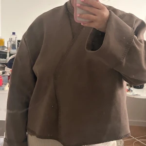 Brun jacka från Gina Tricot - Säljer en brun jacka från Gina Tricot i storlek XL. Jackan har en unik omlott-design med långa ärmar och en stilren look. Den är liten i storleken jag har vanligtvis en M.