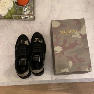 Valentino rockrunners - Snygga Valentino rockrunners med kamouflage i svart och beige samt lite guld. Helt nytt skick säljer prå grund av att de är för små. Box, dustbag och äkthetsbevis medföljer. Priset är inte hugget i sten och var inte rädd att fråga om mer information! Kan pruta ner vid snabb affär.