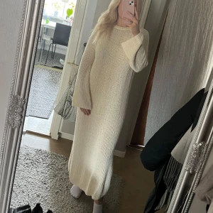 Offwhite stickad långklänning  - En lång stickad klänning i ett slubgarn som ger klänningen en härlig struktur. Klänningen har slits i sidan och vidare ärm, en rundad hals och ribbat avslut i hals och ärm. 82% bomull. Strl S men funkar även som M beroende på hur man vill att den ska sitta. Ord.pris 799:- 
