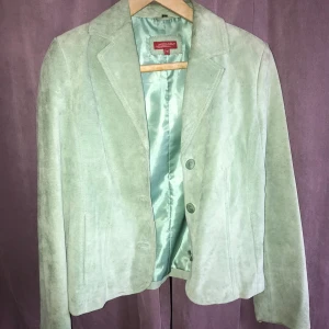 Grön mockakavaj från Enz-A - Snygg ljusgrön mockakavaj från Enz-A i storlek 38. Kavajen har en klassisk design med knappar framtill. Perfekt italiensk look! Obs några missfärgningar här å var om man kollar för noga.