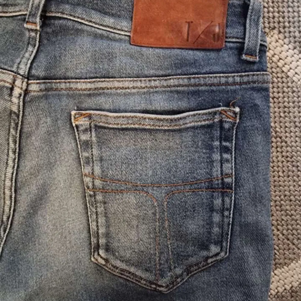 Snygga blå jeans med en klassisk femficksdesign och slitningar för en trendig look. De har en knappgylf och bälteshällor. Perfekta för en avslappnad stil.. Farkut & Housut.
