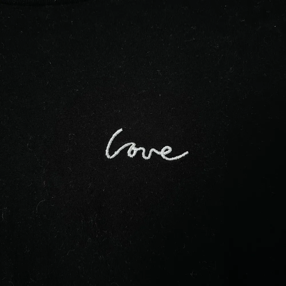 Säljer en stilren svart t-shirt från H&M Divided med en liten vit broderad text 'love' på bröstet. T-shirten har korta ärmar och en klassisk rund halsringning. Perfekt för en avslappnad look 🖤 Önskar du veta exkta mått? Tveka inte att höra av dig! . T-paidat.