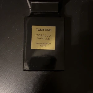 Tom For Tobacco Vanille Eau de Parfum - Säljer en lyxig Tom FordTobacco Vanille Eau de Parfum i en elegant svart flaska med guldetikett. Doften är en rik blandning av tobak och vanilj, perfekt för den som vill ha en djup och sofistikerad doft. Flaskan rymmer 100 ml och kommer i en stilren förpackning.