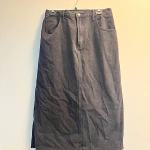 Svart kjol från Shein - Snygg svart långkjol från Shein i jeansmaterial. Kjolen har en klassisk design med fickor både fram och bak samt en knapp och dragkedja framtill. Perfekt för en stilren look.