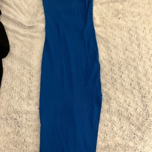 Blå klänning från newyorker - Snygg blå klänning från Amisu i en smickrande lång modell. Perfekt för en stilren look. Klänningen har en enkel design med smala axelband och är tillverkad i ett mjukt material.