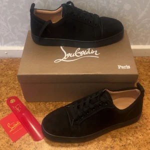 Louboutin skor  - Snygga svarta sneakers från Christian Louboutin i mocka med klassisk röd sula och diskret logga undertill. Skorna har rund tå, svarta snören och en stilren design som passar perfekt till streetwear eller en mer dressad look. Pris kan diskuteras. Kvitto finns!!!