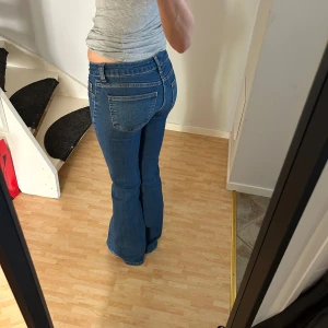 Blå bootcut jeans - Snygga blå jeans från med bootcut passform och låg midja. Från HM. Kommer ej till anvöndning. I storlek 32 men jag brukar normalt ha 34.