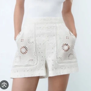 Vita broderade shorts från Zara - Snygga vita shorts från Zara med hög midja och broderade blommönster. De har en loose passform, fickor på sidorna och är gjorda i bomull med spetsdetaljer. Perfekta för sommarens alla häng, riktigt fräscha och trendiga.