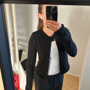 Svart stickad kofta från Gina Tricot - Mysig svart stickad kofta från Gina Tricot i storlek XXS. Koftan har rund hals, knappar hela vägen och långa ärmar. Är tyvärr för liten för mig. Har bara används ett fåtal gånger.