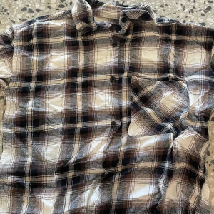 Rutig skjorta från 157 i brun och svart - Riktigt snygg rutig skjorta från 157 i bruna, svarta och vita toner. Skjortan har lång ärm, klassisk krage, knappar framtill och en bröstficka. Perfekt för dig som gillar en avslappnad och cool stil. Pyjamas som är skön finns även matchande byxor i min profil.