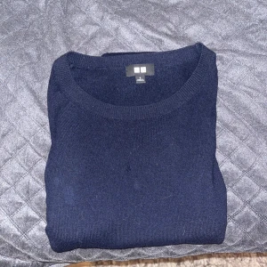 Mörkblå stickad tröja från Uniqlo - En stilren chasmir mörkblå tröja, perfekt för höst, vinter och vår. Den här slim fitt passform och är rätt stor i storleken. Tröjan har några hål i sig därav det billiga priset, säljer tröjan pga för stor för mig! Hör av dig om har funderingar.