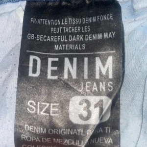 Blå Calvin Klein jeans, storlek 31 - Snygga blå jeans från Calvin Klein i klassisk modell med raka ben och slitna detaljer framtill. Jeansen har fem fickor, tydliga sömmar och ett stort CK-läderpatch bak i midjan. Perfekta för dig som gillar en avslappnad och trendig look.