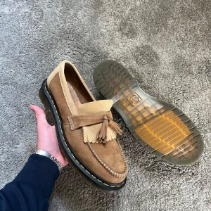 Dr. Martens Adrian loafers mocka - Säljer ett par bruna loafers från Dr. Martens i storlek 43 i mjuk mocka med klassisk tofs och dekorativ söm framtill. Nästan nyskick 