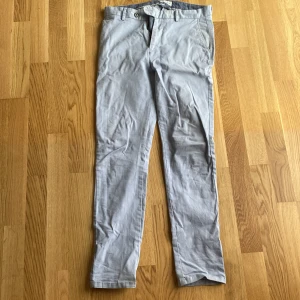 Ljusblå chinos från John Henric W32 - Snygga ljusblå chinos från John Henric i bomull med lite stretch. Klassisk rak passform med bälteshällor, knapp och dragkedja. Perfekta för en clean och stilren look. Passar dig som är ca 183-187.