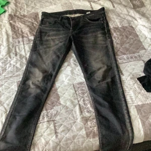 Svarta jeans från True Religion - Snygga svarta jeans från True Religion med klassiska hästsko-sömmar på bakfickorna. Jeansen har en rak passform, fem fickor och coola slitningar framtill. Perfekta för dig som gillar streetwear och vill ha en unik look.